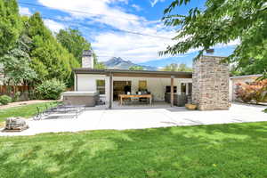 Rear view of house with outdoor lounge area, a mountain view, a patio, a lawn, and a hot tub