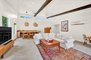 Living room featuring beverage cooler, beamed ceiling, a towering ceiling, and light carpet