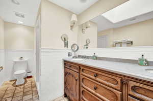 Bathroom with backsplash, toilet, vanity, and tile walls