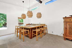 Carpeted dining room featuring a high ceiling, beam ceiling, and a healthy amount of sunlight