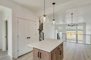 Kitchen with light wood-type flooring, hanging light fixtures, an inviting chandelier, and a center island