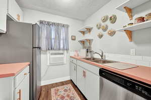 Kitchen with dark hardwood / wood-style flooring, stainless steel appliances, sink, and white cabinets