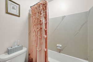 Bathroom with toilet and shower / tub combo with curtain