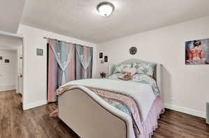 Bedroom with dark hardwood / wood-style floors and a textured ceiling