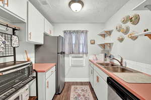 Kitchen featuring a textured ceiling, stainless steel appliances, sink, and white cabinets