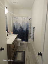 Full bathroom with toilet, hardwood / wood-style flooring, vanity, and shower / bathtub combination with curtain