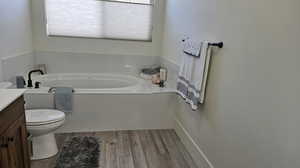 Bathroom with vanity, a bathtub, toilet, and hardwood / wood-style floors