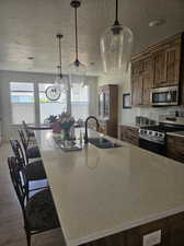 Kitchen featuring tasteful backsplash, stainless steel appliances, wood-type flooring, sink, and light stone countertops