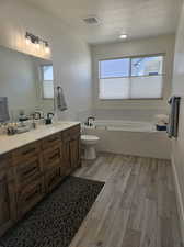 Bathroom featuring vanity, toilet, wood-type flooring, and a tub