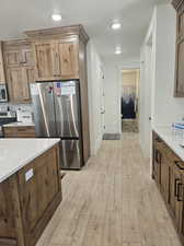 Kitchen featuring a textured ceiling, stainless steel appliances, light stone countertops, and light wood-type flooring