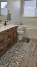 Bathroom featuring vanity, a tub, wood-type flooring, and toilet