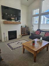 Carpeted living room featuring high vaulted ceiling and a fireplace