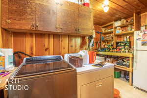 Laundry area featuring wood ceiling, wooden walls, cabinets, and independent washer and dryer