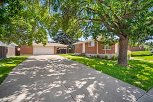 Single story home featuring an outbuilding, a carport, a garage, and a front yard