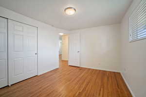 Unfurnished bedroom featuring a closet and light hardwood / wood-style floors