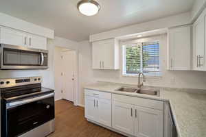 Kitchen with white cabinetry, appliances with stainless steel finishes, sink, and dark hardwood / wood-style flooring