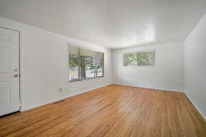 Empty room featuring wood-type flooring and a textured ceiling