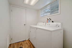 Laundry area with light hardwood / wood-style floors and washer and clothes dryer