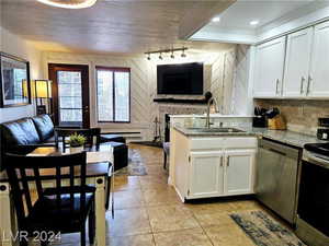 Kitchen with appliances with stainless steel finishes, ornamental molding, sink, light stone counters, and white cabinets