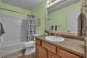 Full bathroom featuring wood-type flooring, vanity, toilet, shower / bathtub combination with curtain, and a textured ceiling