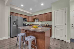 Kitchen with sink, a breakfast bar area, stainless steel appliances, a kitchen island, and light wood-type flooring