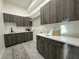 Kitchen with dark brown cabinetry, light stone countertops, and sink