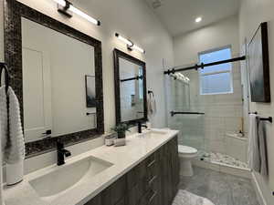 Bathroom with a shower with door, vanity, and toilet