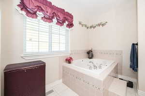 Primary Bathroom with a relaxing tiled tub and tile patterned flooring