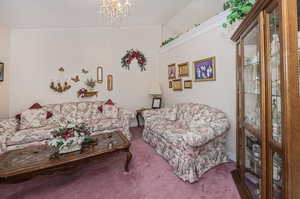 Carpeted living room featuring a notable chandelier and lofted ceiling