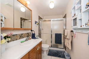 Bathroom featuring tile patterned flooring, vanity, walk in shower, and toilet