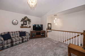 Carpeted living room featuring lofted ceiling and a chandelier