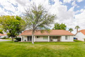 Back of property with central AC unit and a lawn