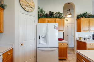 Kitchen featuring white refrigerator with ice dispenser and light tile patterned flooring