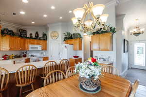 Tiled dining room with sink, crown molding, and a chandelier