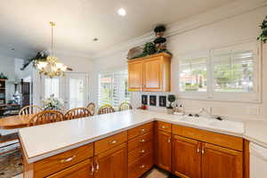 Kitchen with kitchen peninsula, a healthy amount of sunlight, white dishwasher, and sink