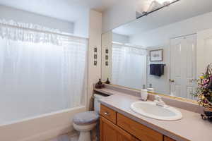 Full bathroom with tile patterned flooring, shower / bath combination with curtain, vanity, and toilet