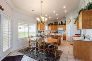 Tiled dining room with lofted ceiling, a notable chandelier, and ornamental molding