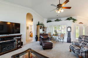 Carpeted living room featuring ceiling fan, vaulted ceiling, ornamental molding, and french doors