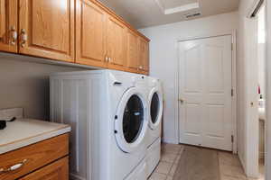 Clothes washing area featuring light tile patterned floors, independent washer and dryer, and cabinets