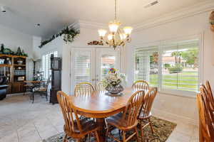 Tiled dining room featuring a healthy amount of sunlight, a chandelier, and ornamental molding