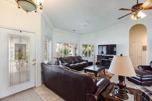 Tiled living room with ceiling fan and crown molding