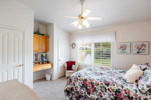 Bedroom featuring ceiling fan, light colored carpet, and lofted ceiling