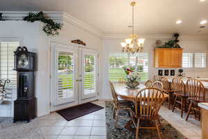 Dining space featuring a notable chandelier, crown molding, and light tile patterned flooring