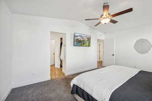 Carpeted bedroom with ceiling fan and vaulted ceiling