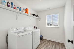 Laundry area with washing machine and dryer and light hardwood / wood-style flooring