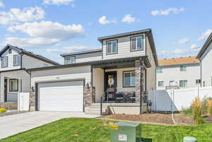 View of front of property featuring covered porch, a garage, and a front yard