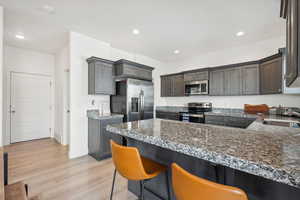 Kitchen with a breakfast bar, appliances with stainless steel finishes, light hardwood / wood-style floors, sink, and kitchen peninsula