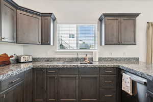 Kitchen featuring stainless steel dishwasher, sink, and dark brown cabinetry