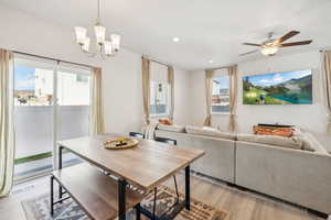 Dining room with light hardwood / wood-style flooring and ceiling fan with notable chandelier