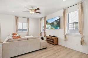 Living room featuring ceiling fan and light hardwood / wood-style flooring